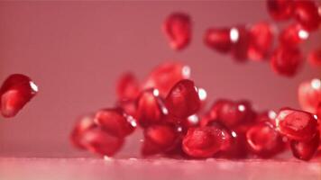 Pomegranate seeds fall on the table with splashes. Filmed on a high-speed camera at 1000 fps. High quality FullHD footage video