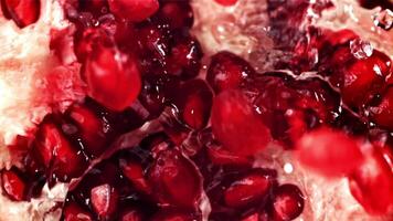 Splashed water pours onto fresh pomegranates. Filmed on a high-speed camera at 1000 fps. High quality FullHD footage video
