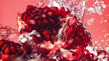 Splashed water pours onto fresh pomegranates. Filmed on a high-speed camera at 1000 fps. High quality FullHD footage video