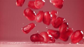 Pomegranate seeds fall on the table with splashes. Filmed on a high-speed camera at 1000 fps. High quality FullHD footage video