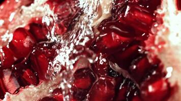Splashed water pours onto fresh pomegranates. Filmed on a high-speed camera at 1000 fps. High quality FullHD footage video