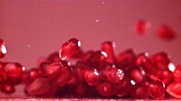 Pomegranate seeds fall on the table with splashes. Filmed on a high-speed camera at 1000 fps. High quality FullHD footage video