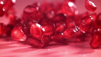 Pomegranate seeds fall on the table with splashes. Filmed on a high-speed camera at 1000 fps. High quality FullHD footage video