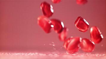 Pomegranate seeds fall on the table with splashes. Filmed on a high-speed camera at 1000 fps. High quality FullHD footage video