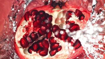 Splashed water pours onto fresh pomegranates. Filmed on a high-speed camera at 1000 fps. High quality FullHD footage video