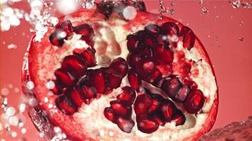 Splashed water pours onto fresh pomegranates. Filmed on a high-speed camera at 1000 fps. High quality FullHD footage video