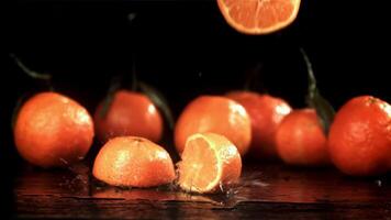 Slices of fresh tangerines falling on black background. Filmed on a high-speed camera at 1000 fps. High quality FullHD footage video