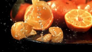 Tangerine slices fall into a wet plate with splashes. Filmed on a high-speed camera at 1000 fps. High quality FullHD footage video