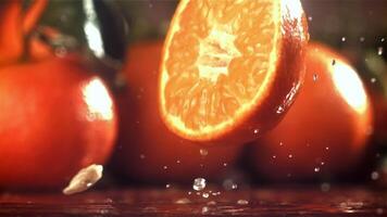 Hälfte ein Mandarine Stürze auf ein nass Tisch. gefilmt auf ein schnelle Geschwindigkeit Kamera beim 1000 fps. hoch Qualität fullhd Aufnahmen video