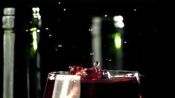 A drop falls into a glass of wine. On a black background. Filmed on a high-speed camera at 1000 fps. High quality FullHD footage video