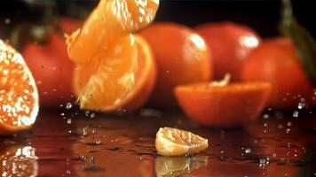 Slices of fresh tangerines fall on a wooden table. Filmed on a high-speed camera at 1000 fps. High quality FullHD footage video