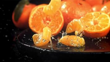 mandarijn plakjes vallen in een nat bord met spatten. gefilmd Aan een hoge snelheid camera Bij 1000 fps. hoog kwaliteit full HD beeldmateriaal video