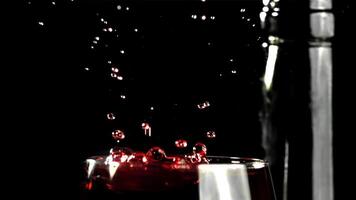 une laissez tomber chutes dans une verre de du vin. sur une noir Contexte. filmé sur une haute vitesse caméra à 1000 ips. haute qualité Full HD métrage video