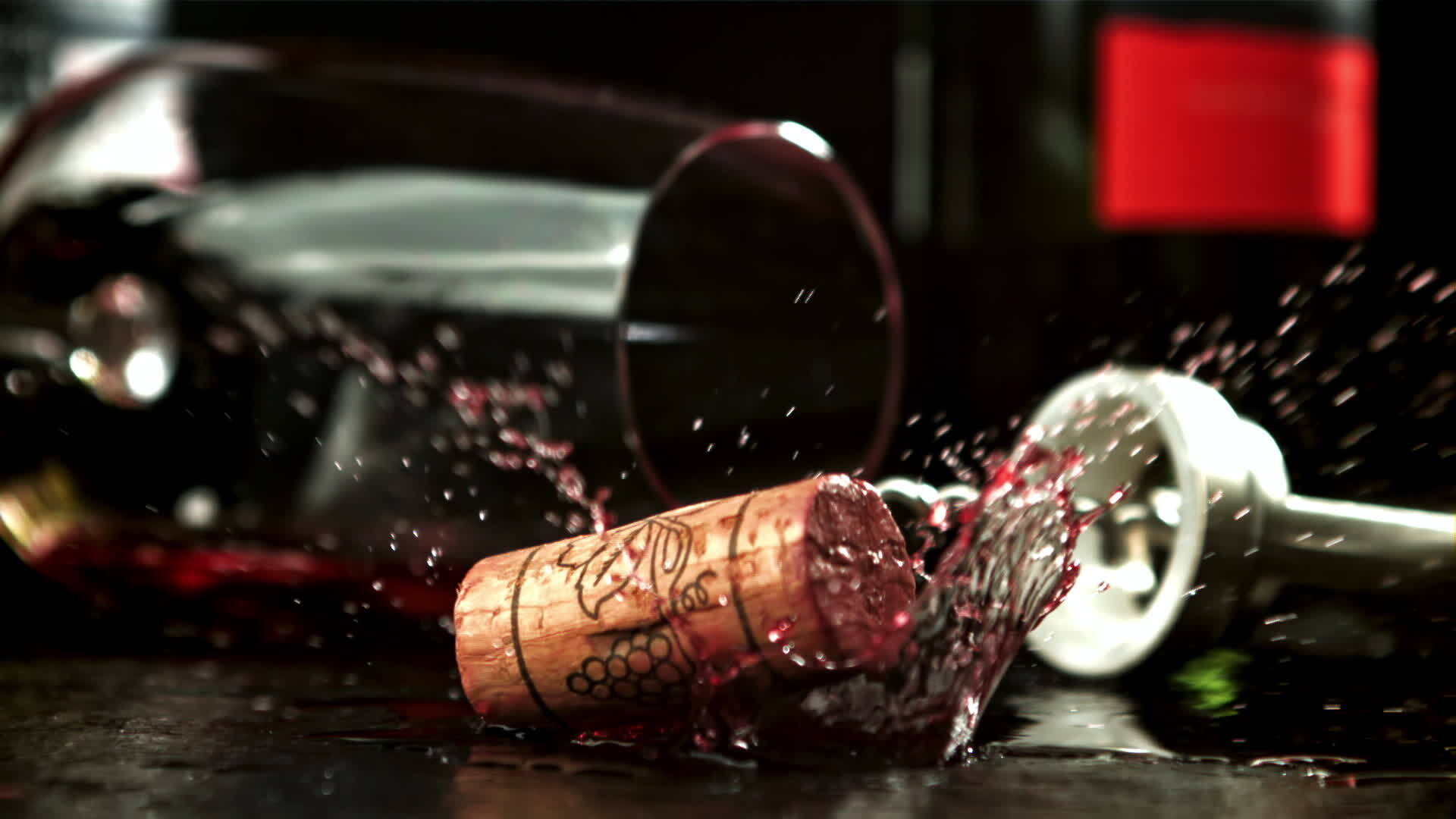 The cork from the bottle falls into the red wine with splashes. Filmed