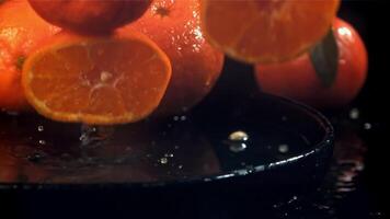 Tangerine slices fall into a wet plate with splashes. Filmed on a high-speed camera at 1000 fps. High quality FullHD footage video