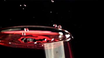 A drop falls into a glass of wine. On a black background. Filmed on a high-speed camera at 1000 fps. High quality FullHD footage video