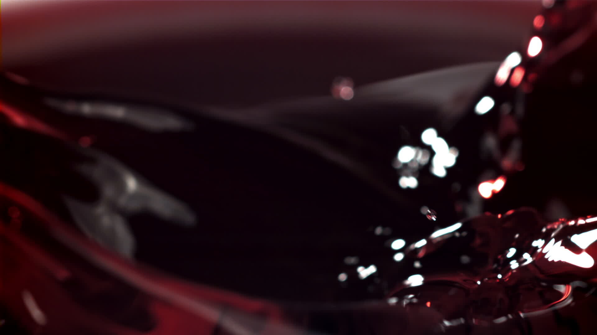 The cork from the bottle falls into the red wine with splashes. Filmed