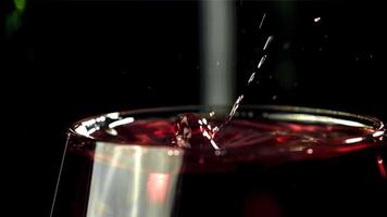 A drop falls into a glass of wine. On a black background. Filmed on a high-speed camera at 1000 fps. High quality FullHD footage video