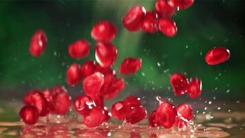 Pomegranate seeds fall on the table with splashes. Filmed on a high-speed camera at 1000 fps. High quality FullHD footage video