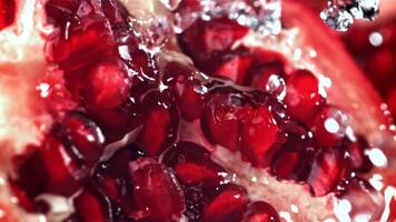 Splashed water pours onto fresh pomegranates. Filmed on a high-speed camera at 1000 fps. High quality FullHD footage video