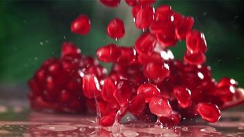 Pomegranate seeds fall on the table with splashes. Filmed on a high-speed camera at 1000 fps. High quality FullHD footage video