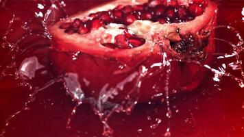 Part of the pomegranate falls into the juice with splashes. Filmed on a high-speed camera at 1000 fps. High quality FullHD footage video