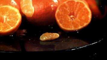 Tangerine slices fall into a wet plate with splashes. Filmed on a high-speed camera at 1000 fps. High quality FullHD footage video