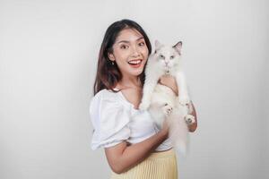 retrato de joven asiático mujer participación linda muñeca de trapo gato con azul ojos. hembra abrazando su linda largo pelo gatito aislado por blanco antecedentes. adorable Doméstico mascota concepto. foto