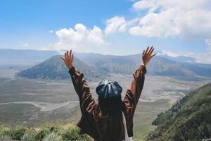 An Asian girl standing on a hill track in Bromo, enjoying view of Bromo, a wonderful scenery in dramatic hill photo