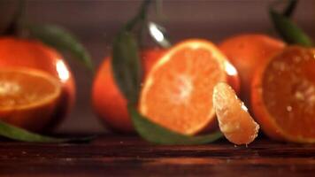 Slices of fresh tangerines fall on a wooden table. Filmed on a high-speed camera at 1000 fps. High quality FullHD footage video