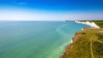 Aerial view of a scenic chalk cliffs coastline with turquoise sea under a clear blue sky. photo