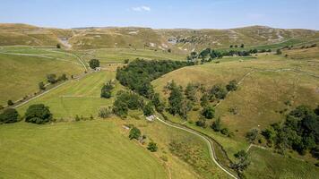 Scenic view of rolling hills with green fields and a country road, under a clear sky. photo