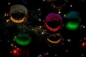 Colorful Christmas baubles on a tree with twinkling lights, creating a festive holiday background. photo