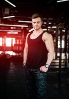 Muscular young man training indoor in the gym. Sporty athletic bodybuilder posing for camera. photo