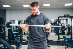 Concentrated bodybuilder working out in modern light gym. Exercises on weightlifting. photo