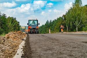 Asphalting of road with steamroller. Asphalt paving machine at construction site photo