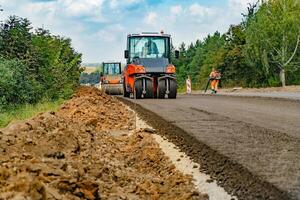 vista cercana de los rodillos de carretera que trabajan en el nuevo sitio de construcción de carreteras. pavimentación de carreteras foto