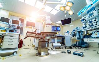 Establishing shot of technologically advanced operating room with no people, ready for surgery. Operating theater with working equipment, lights and computers ready for surgeons. photo