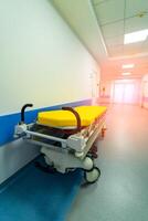 Yellow hospital bed on wheels in wide long modern hall in hospital. photo