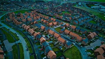 Aerial view of a suburban neighborhood at dusk with rows of houses and winding streets. photo