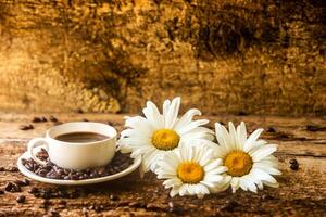 Coffee cup and fried coffee beans on a wooden table with beautiful white flowers on a wood background photo