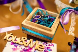 Wedding Decoration. Golden rings in wooden box with colorful ribbons inside. photo