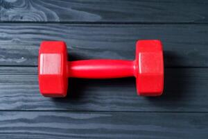 Red dumbbell for fitness isolated on dark background. photo