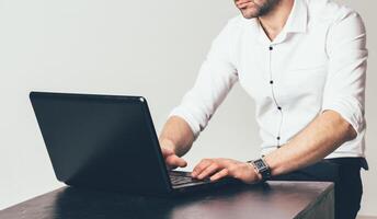 rich man in a luxurious white shirt works at the table in front of the laptop. Business writes a message photo