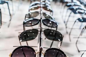Gafas de sol en un almacenar. fila de lujo lente a un ópticos Tienda foto