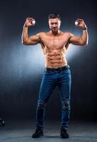 hombres participación dos blanco huevos en un gris antecedentes. carrocero con huevos, desnudo torso. sano estilo de vida concepto, lleno longitud foto. de cerca foto