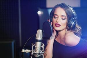 Beautiful young singer who recorded a song in a professional recording studio. Female vocal photo