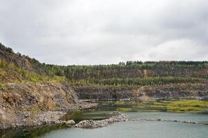 Summer quarry lake in the cliffs with cloudy blue sky, natural landscape background. Panoramic view. photo