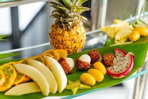 Mixed of many exotic fresh fruits on a glass table for banquet. Group of fresh natural and organic fruits assorted on green leaves. photo