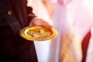Gold wedding rings on the golden plate in the church photo